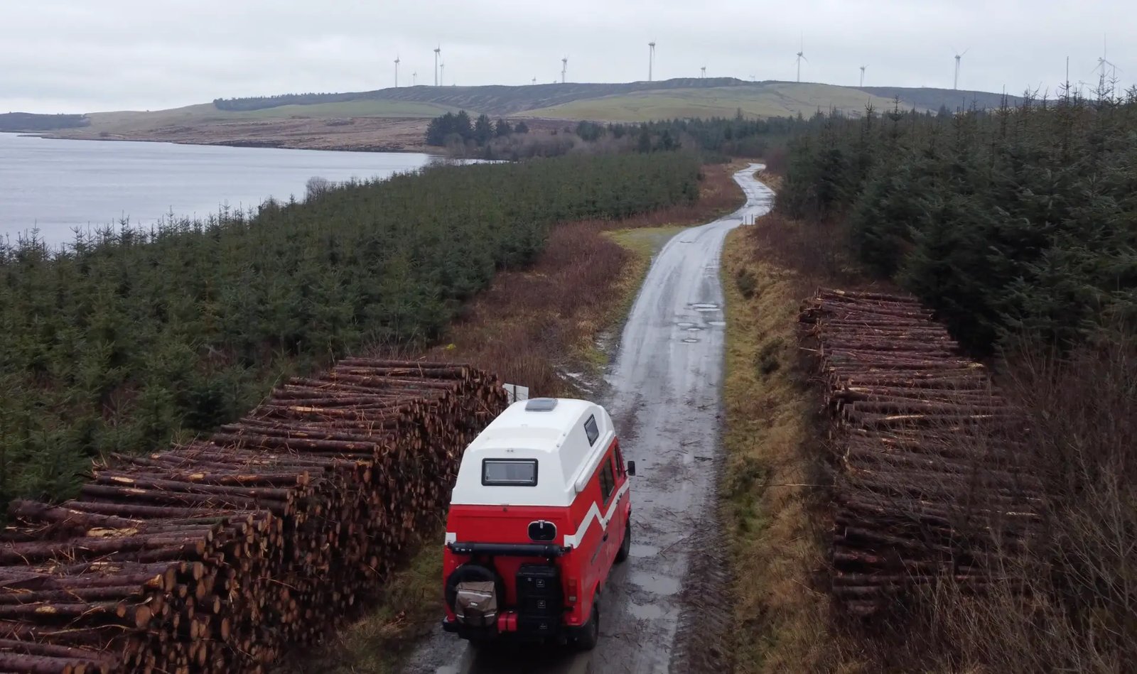 Aerial view of Michael’s red Mercedes T1 campervan on a remote forest track beside a lake