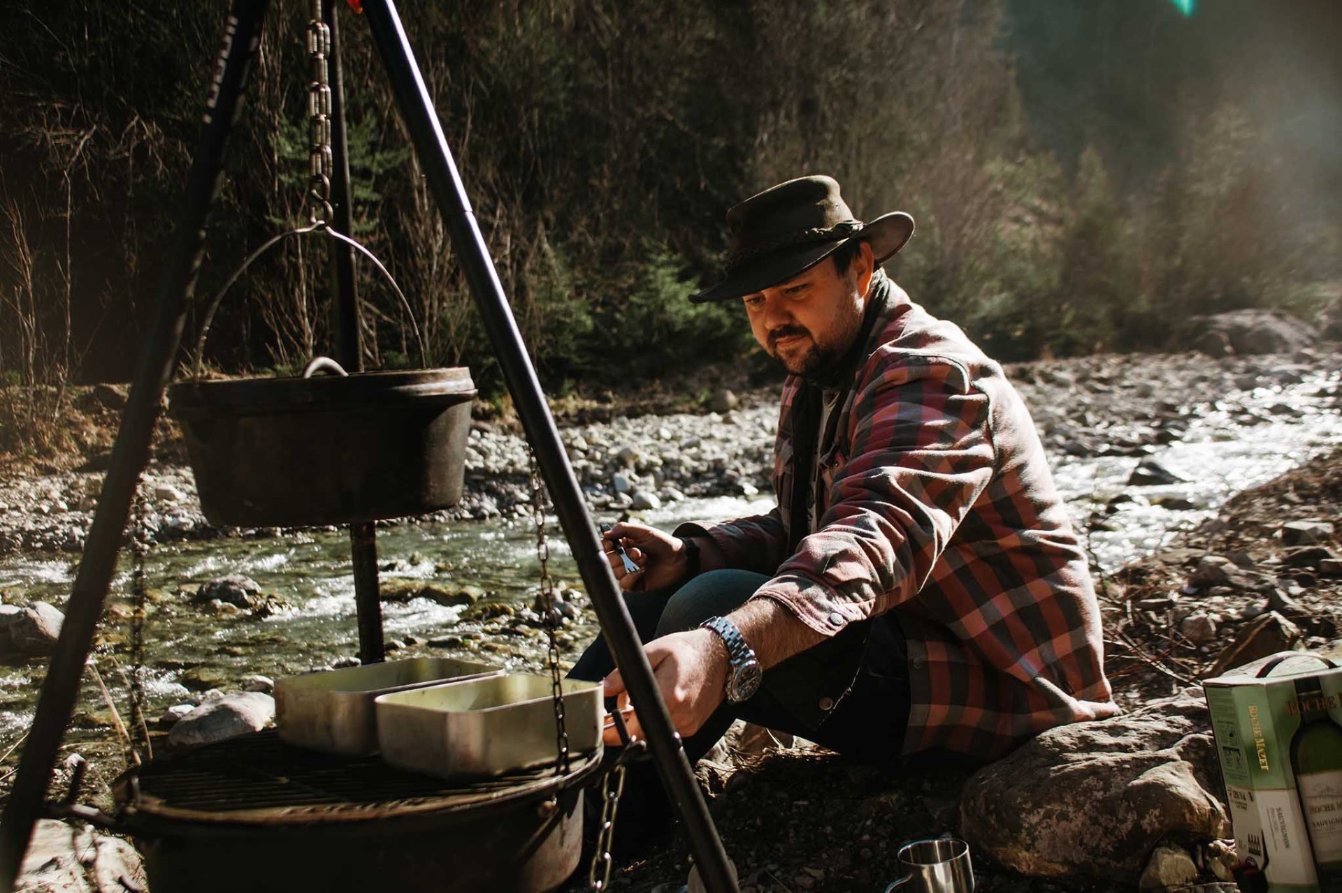 Michael Basco cooking over an open fire beside a mountain river